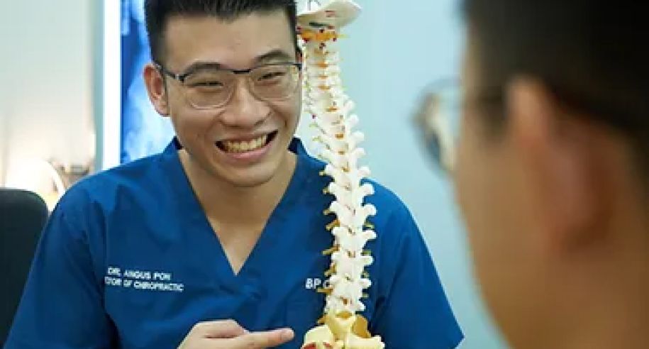 Chiropractor explaining the spine to a patient with a model